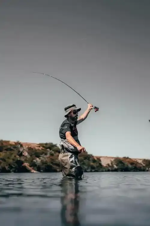 Angler casting from a rocky shoreline on a misty Canadian morning