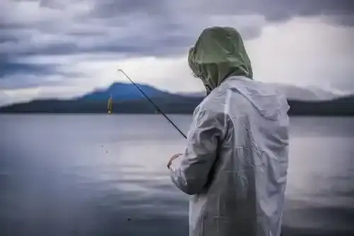 Angler steering a boat across a calm Canadian lake at sunrise