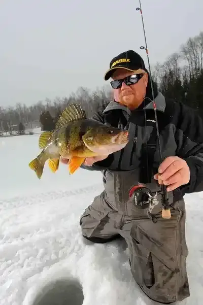 Smiling angler holding a northern pike caught on a Canadian lake