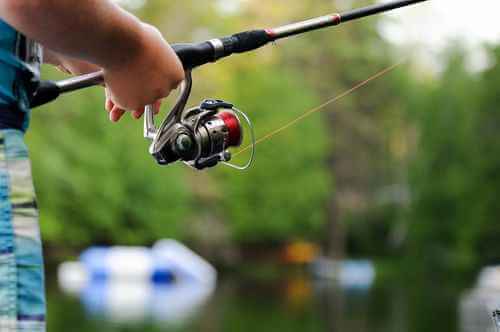 Fishing Club Canada guide demonstrating casting technique on a lakeshore