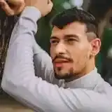 Member Louis Toadvine standing on a lakeshore with a landing net and tackle bag