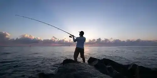 Angler casting from a lakeshore during a Fishing Club Canada event