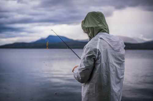 Solo angler standing on rocky shore during a quiet morning session